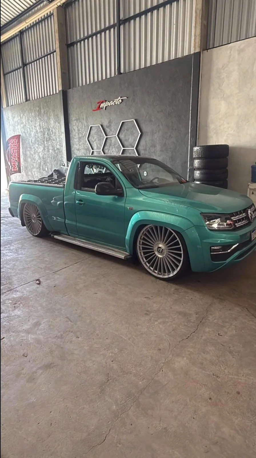 Picape verde com rodas esportivas dentro da oficina
